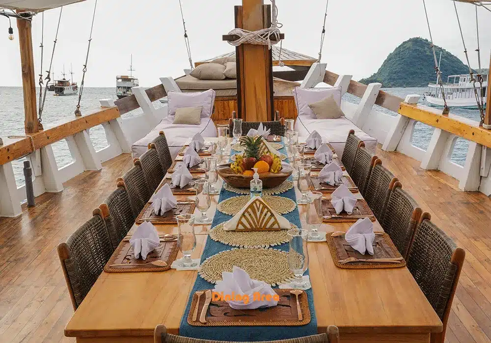 3 days shared trip. Elegant dining setup on a boat with a long table, featuring arranged napkins, fruit centerpiece, and views of the sea.