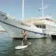 3 days shared trip A man paddleboards near a large white boat named "Mosalaki" docked in calm waters under a clear blue sky.