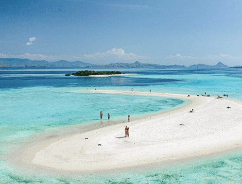 Takak Makassar - Pristine white sand beach curving into turquoise waters, with people enjoying the tropical scenery under a clear blue sky.