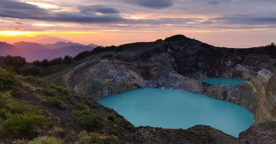 Kelimutu Volcano​ Indonesia. Vibrant sunset over rugged mountains, highlighting turquoise volcanic lakes and dramatic rocky formations.